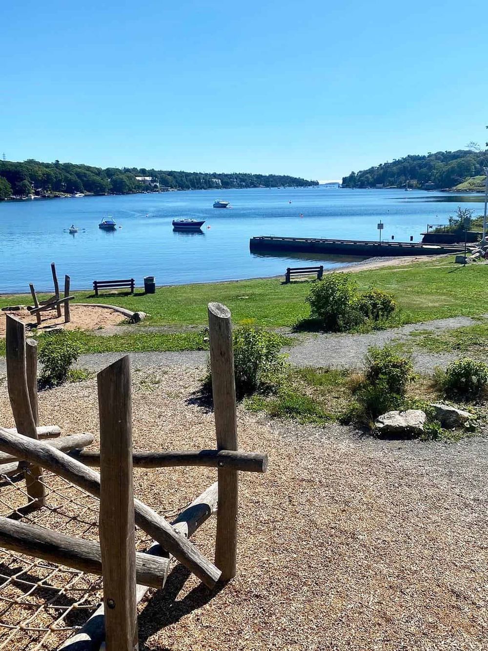 Serene waterfront park with boats, benches, and playground near the water. Perfect for outdoor recreation and scenic views.