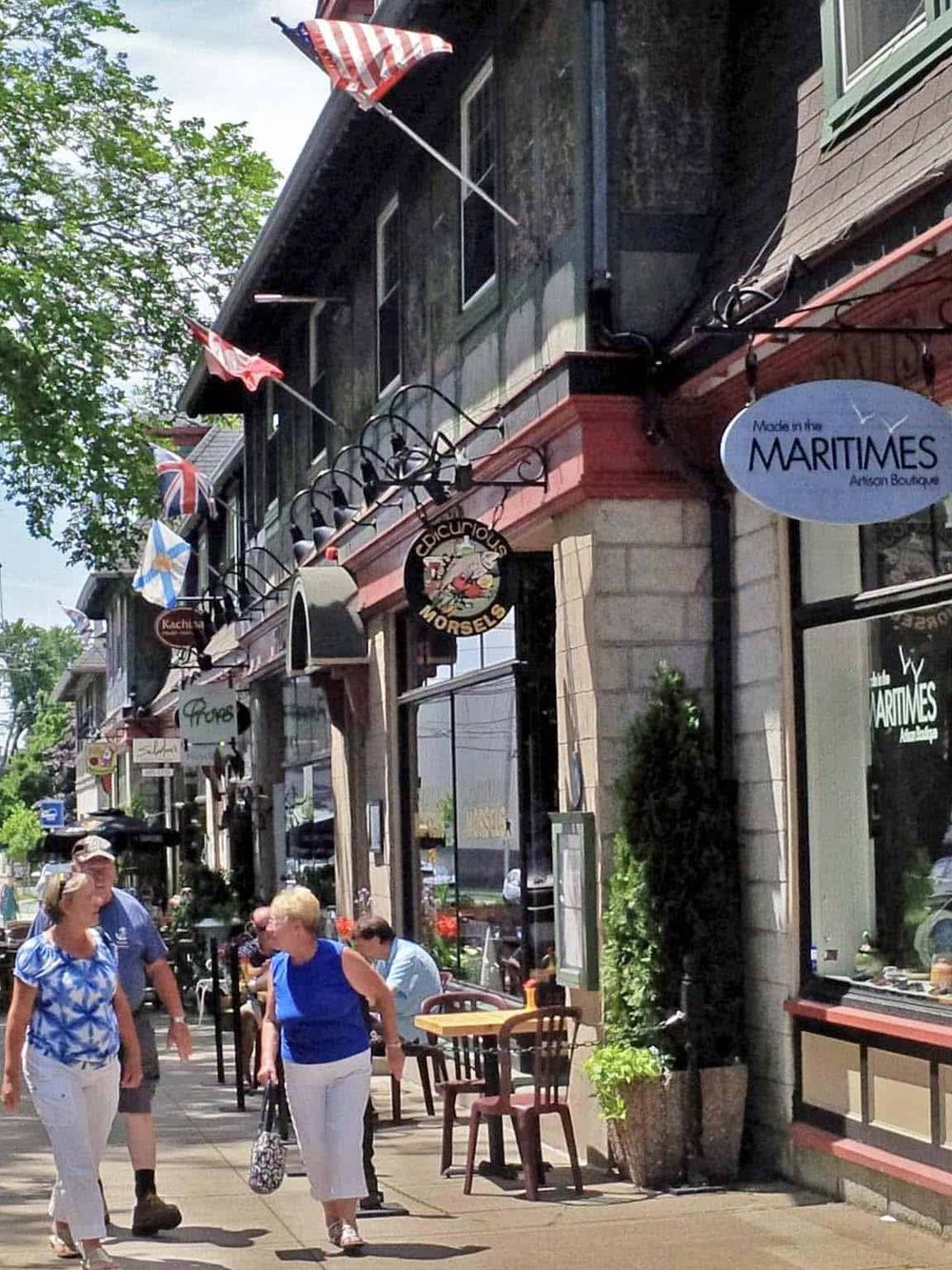 Charming downtown street scene with boutique stores, outdoor seating, and pedestrians, highlighting shopping and dining in a vibrant community.