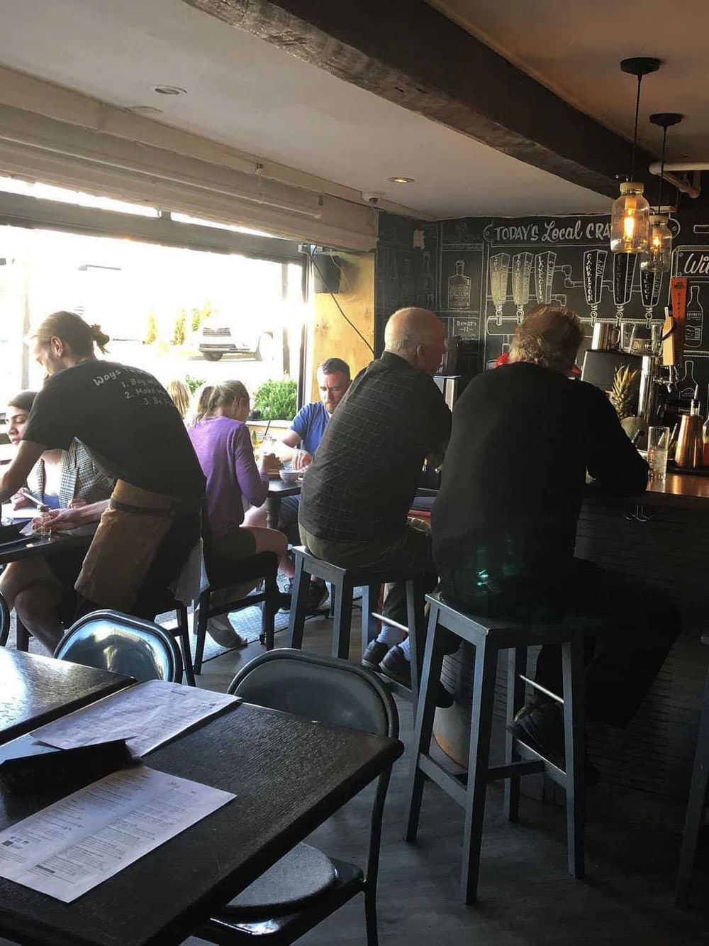 Cozy cafe interior with customers enjoying drinks and food, vibrant atmosphere, natural light, modern decor, perfect for dining or socializing.