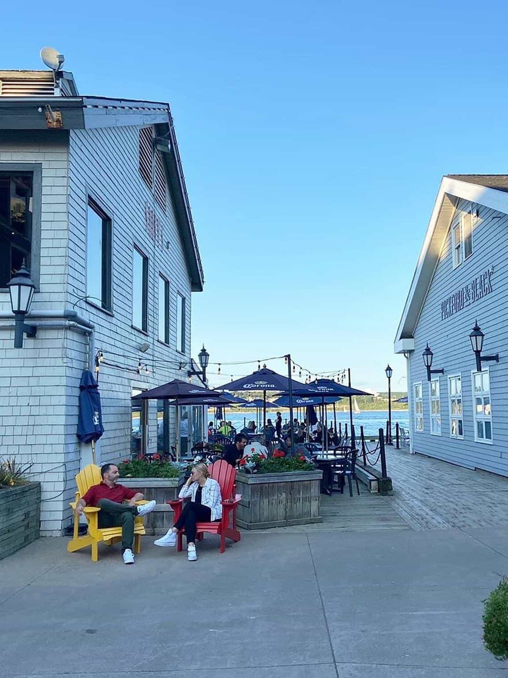 Outdoor waterfront dining in a scenic setting with colorful chairs and string lights.