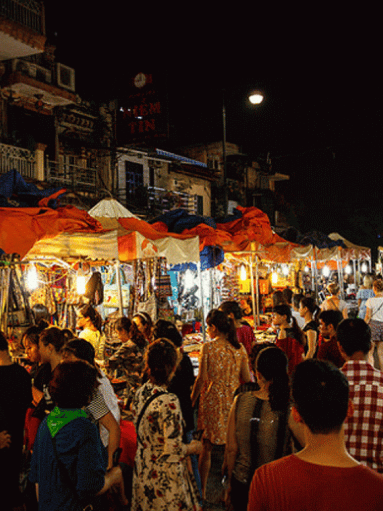 Bustling night market with vibrant stalls and diverse crowd, showcasing lively street food and shopping scene.