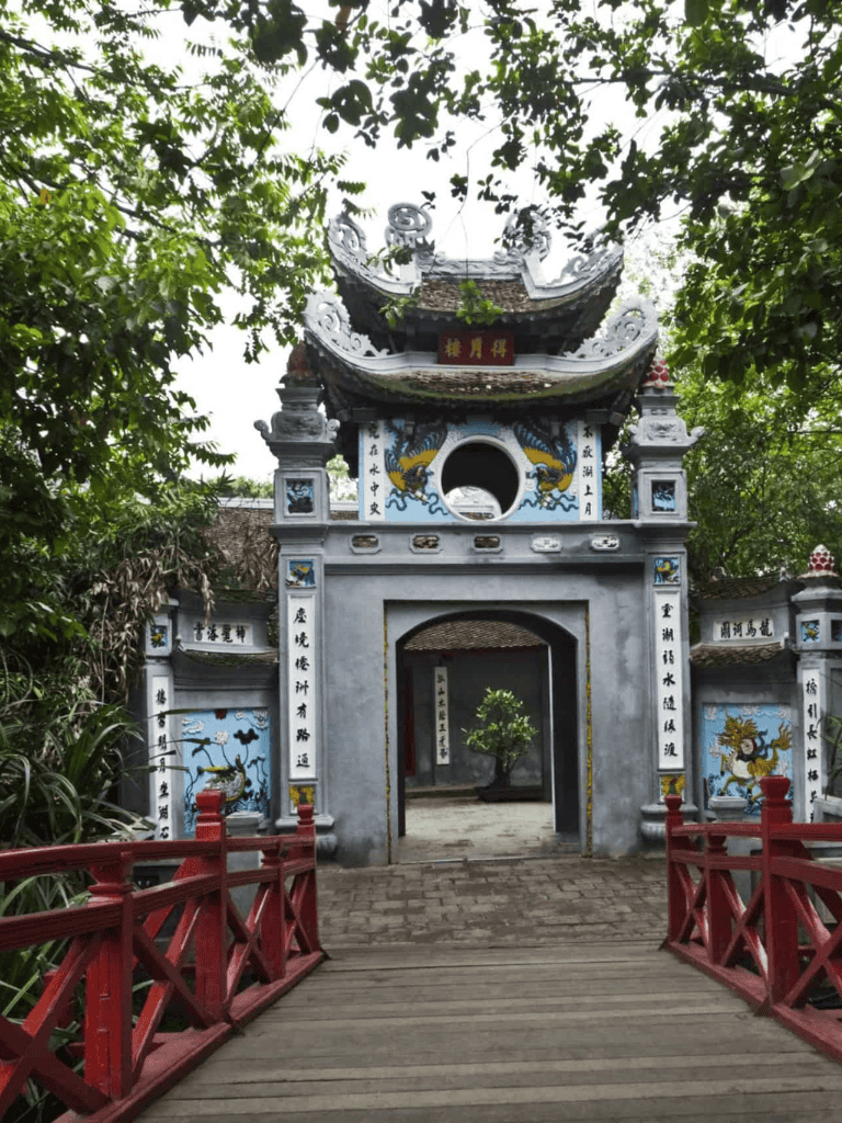 Ancient temple entrance with traditional Asian architecture, surrounded by lush greenery.