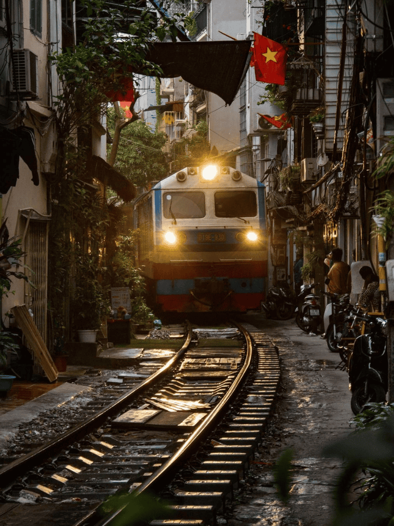 Train running through narrow urban street in Hanoi, Vietnam.
