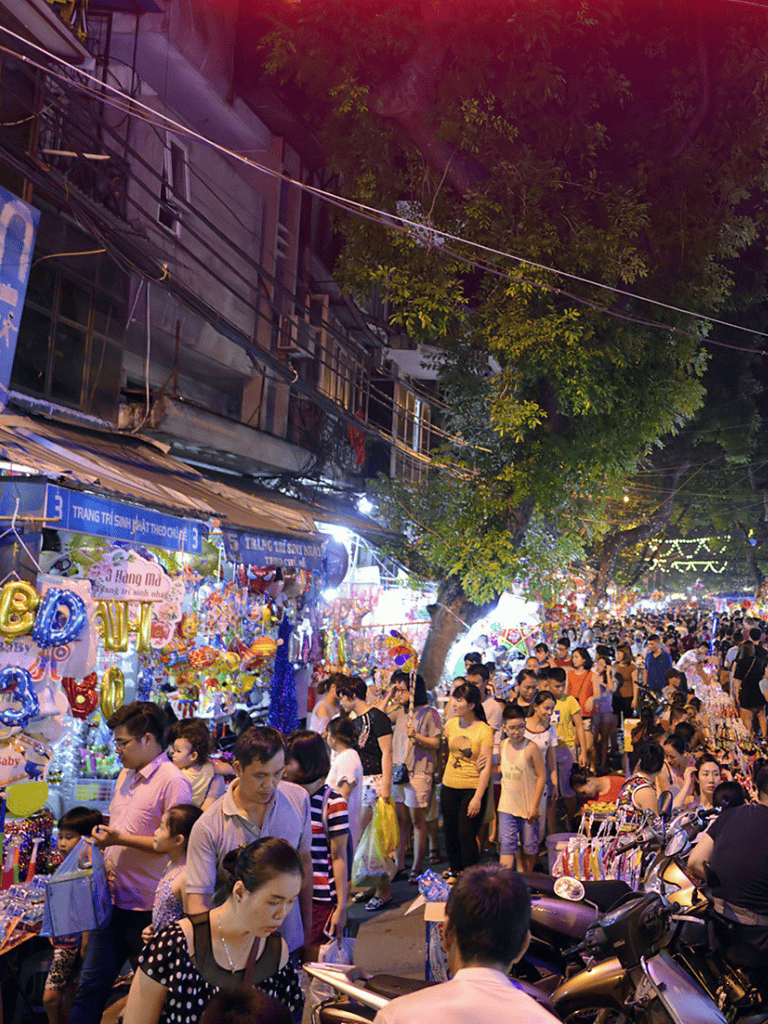 Bustling night market street filled with shoppers, colorful stalls, and vibrant atmosphere in Vietnam.