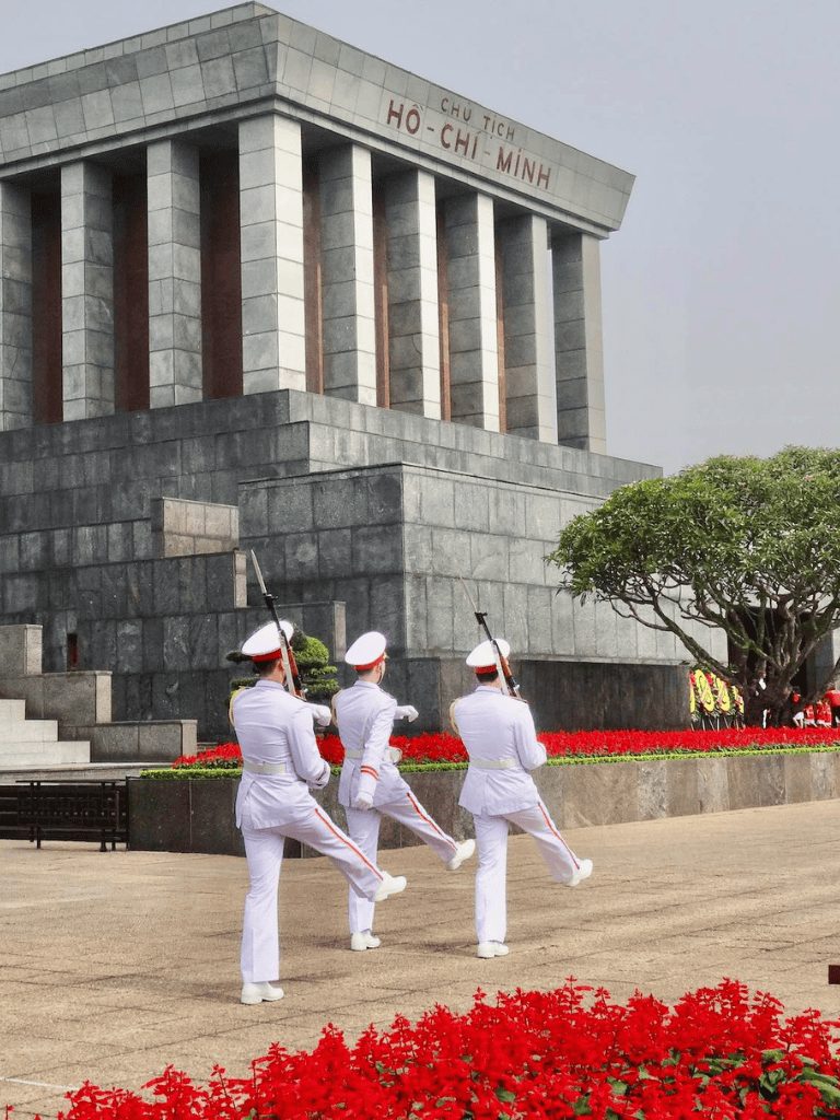 Ceremonial soldiers marching in front of Ho Chi Minh Mausoleum, Vietnam's historical landmark.
