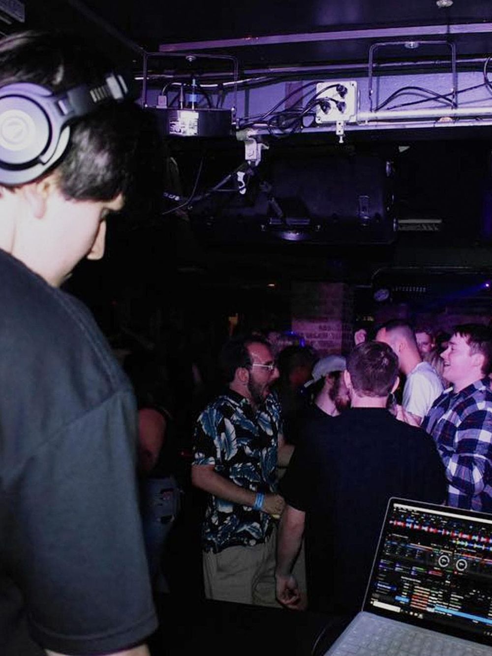 Young DJ mixing music at nightclub event with crowd enjoying dance night.