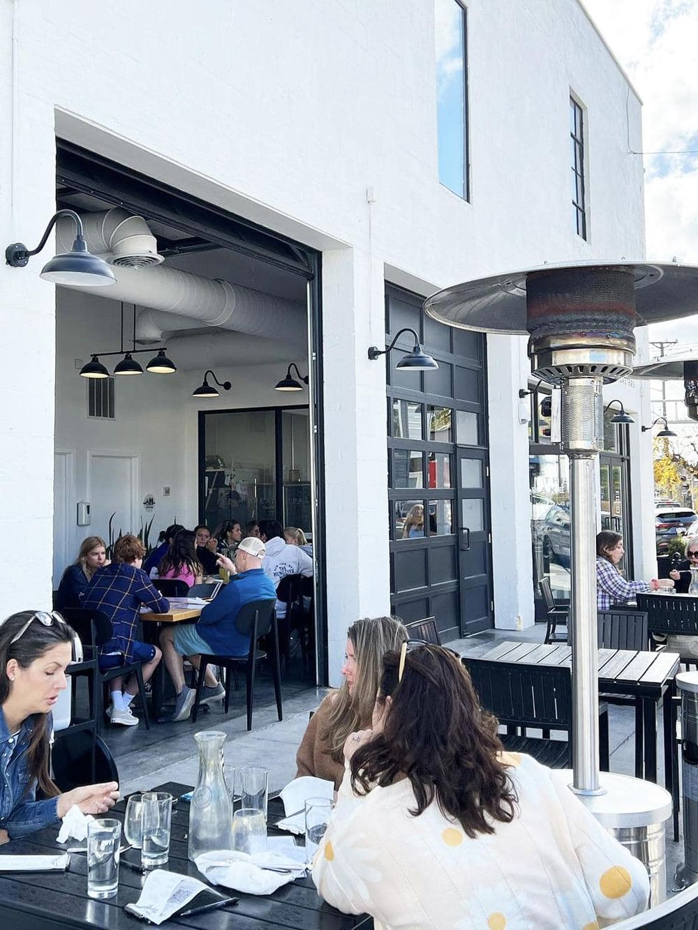 Outdoor dining at a modern, stylish restaurant with heating and industrial lighting. Perfect for casual meals and social gatherings.