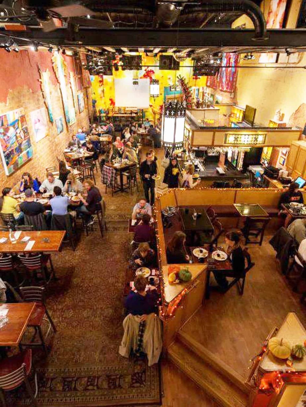 Colorful restaurant interior with artwork, ambient lighting, and diverse guests enjoying meals.