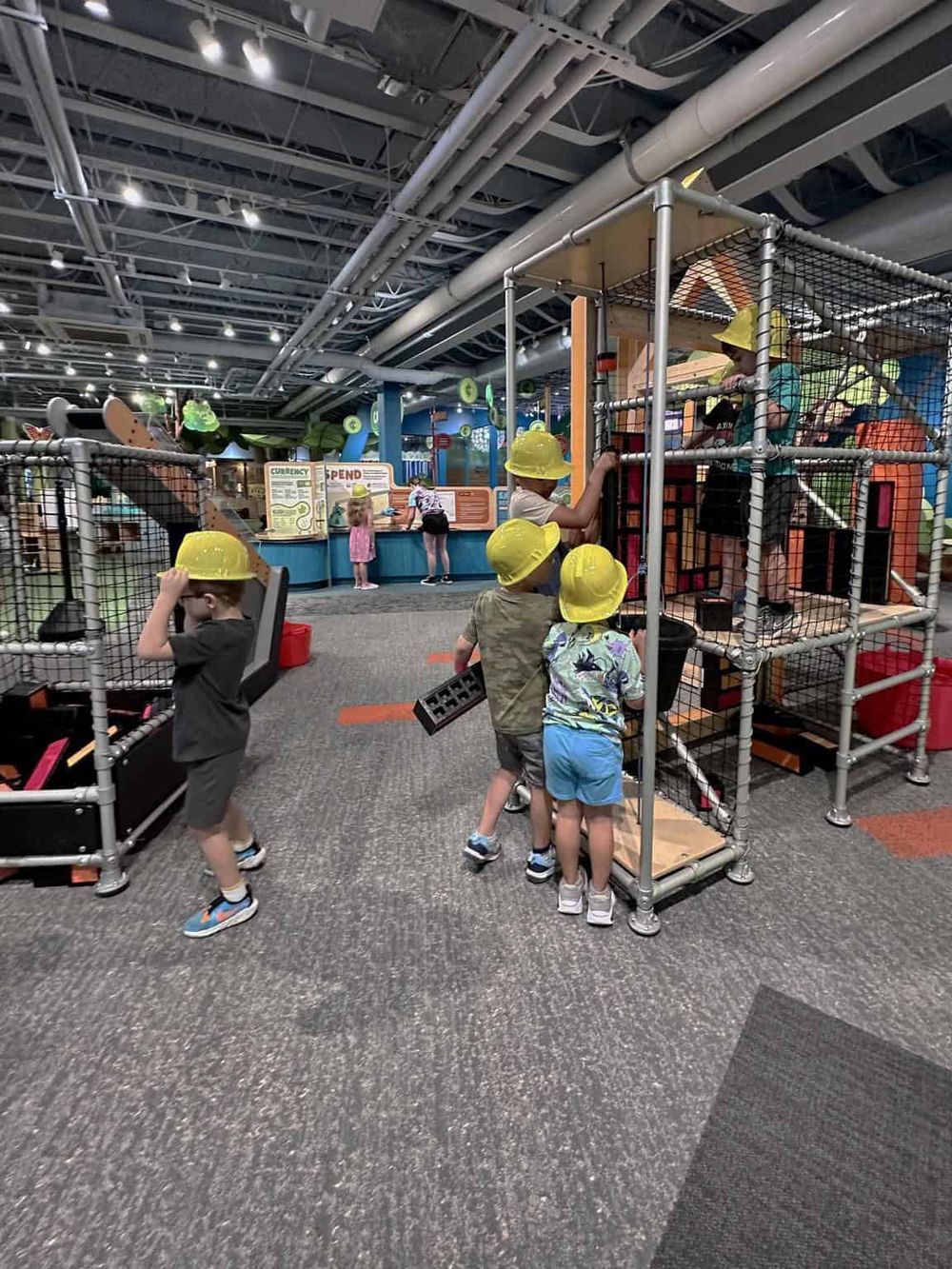 Colorful indoor play area for kids with climbing structures and safety gear.