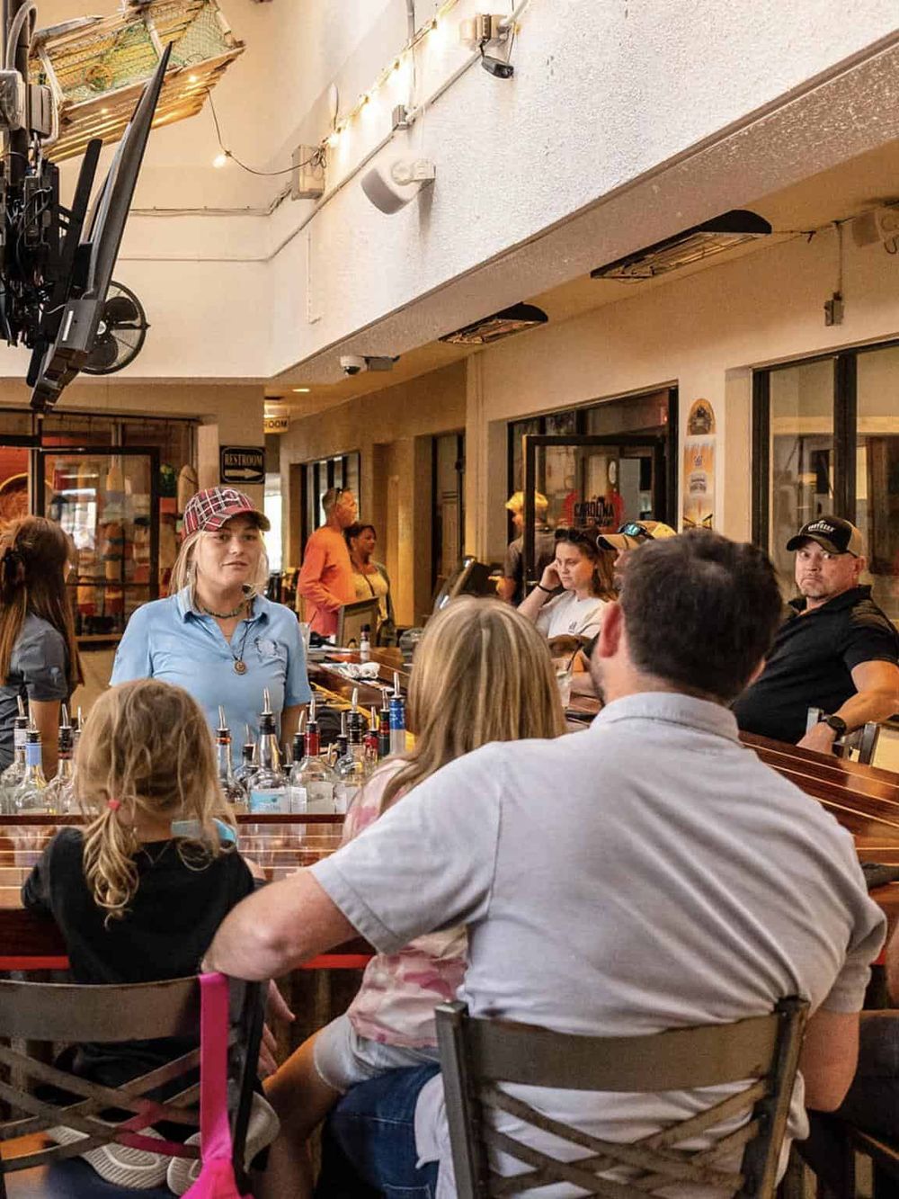 Vibrant indoor restaurant scene with diverse group of guests enjoying drinks, lively atmosphere, and socializing.