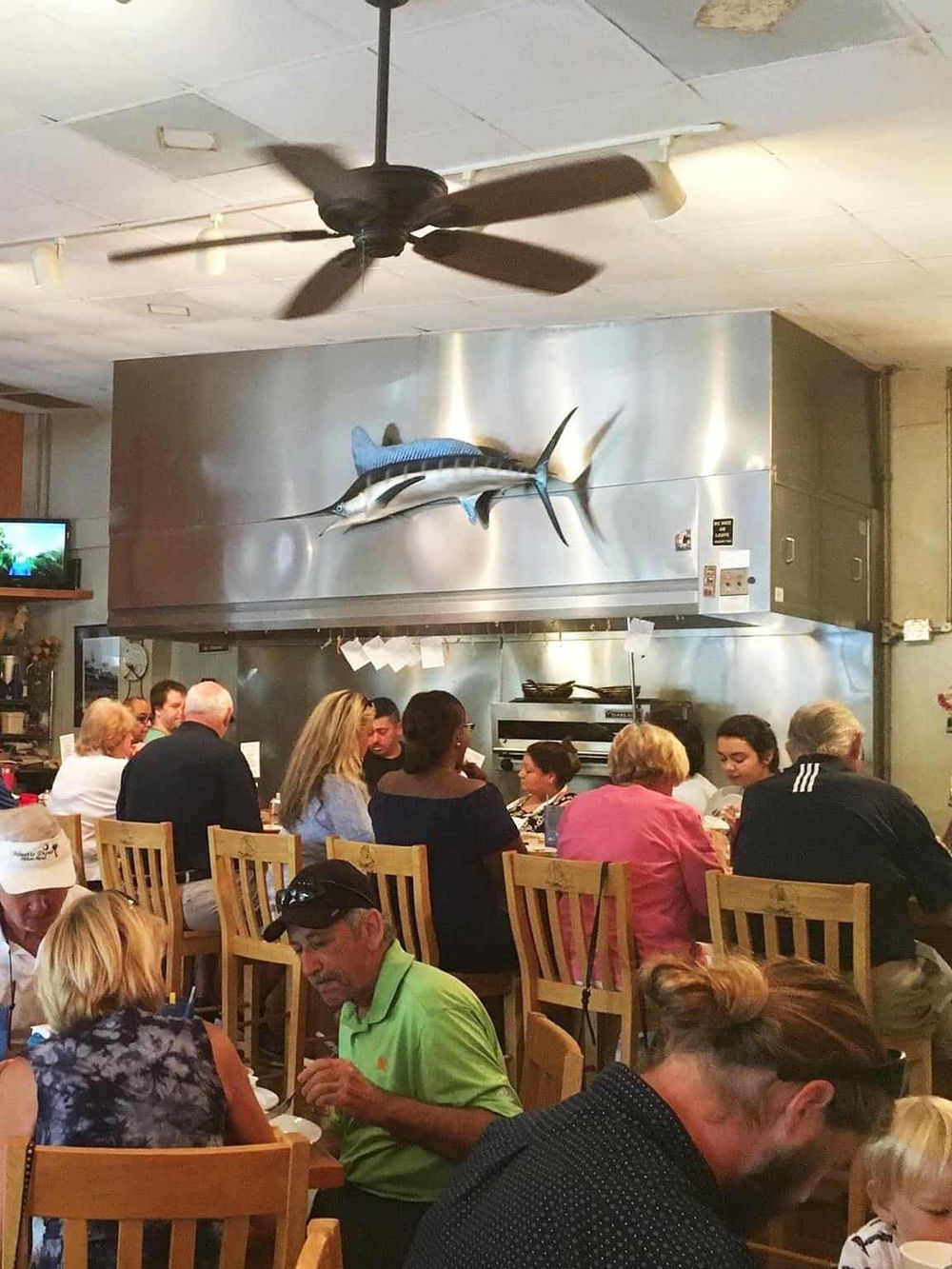 Colorful seafood restaurant interior with diners dining, maritime decor, and a large marlin mounted on the wall.