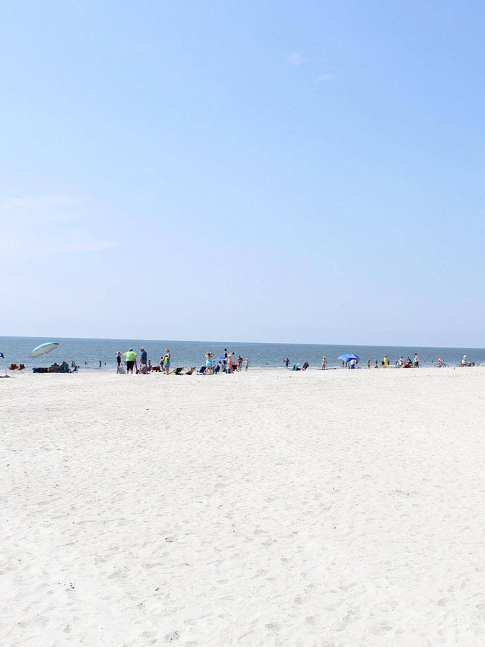Vibrant beach scene with people enjoying a sunny day at the ocean shoreline, perfect for vacation and seaside relaxation.
