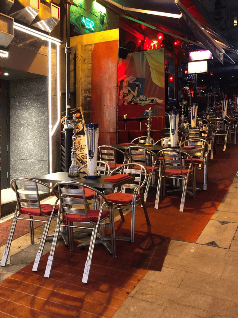Outdoor restaurant seating with hookah on tables, vibrant ambiance, modern decor, nightlife atmosphere, QuestForDirections.