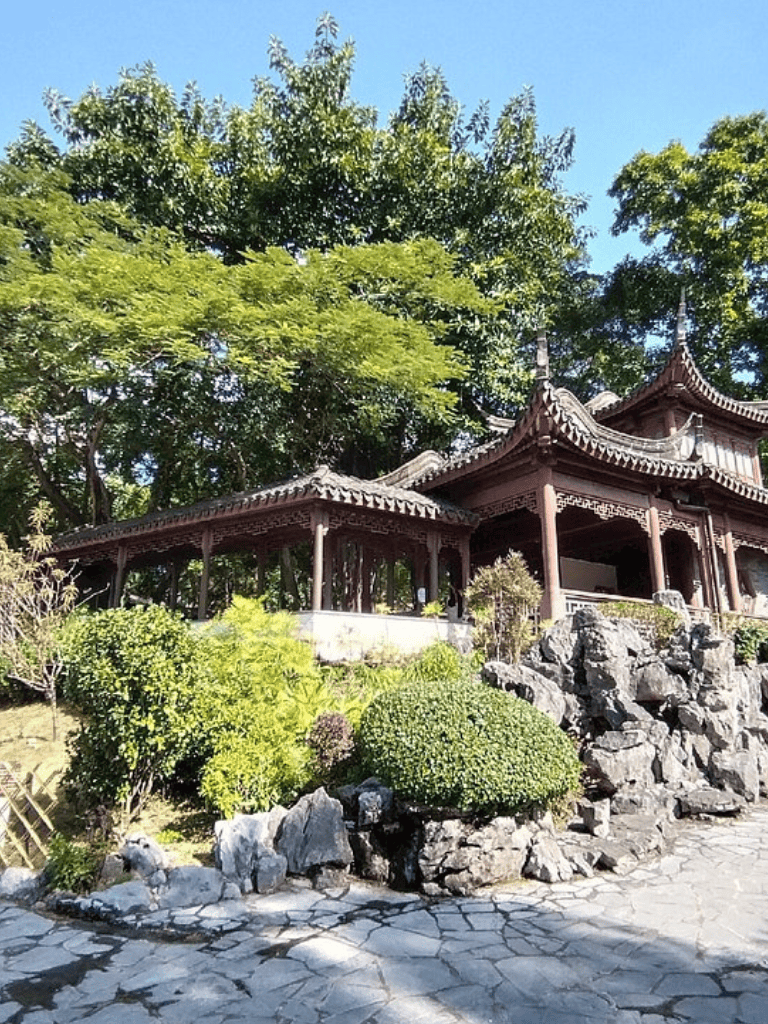 Serene traditional Asian pavilion amidst lush greenery and rocks, ideal for peaceful retreats or garden design.