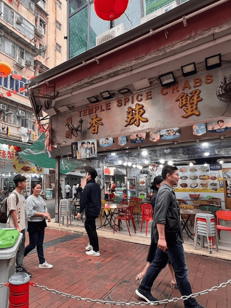 Spice Crabs restaurant exterior in busy Asian street, vibrant dining area, people walking.