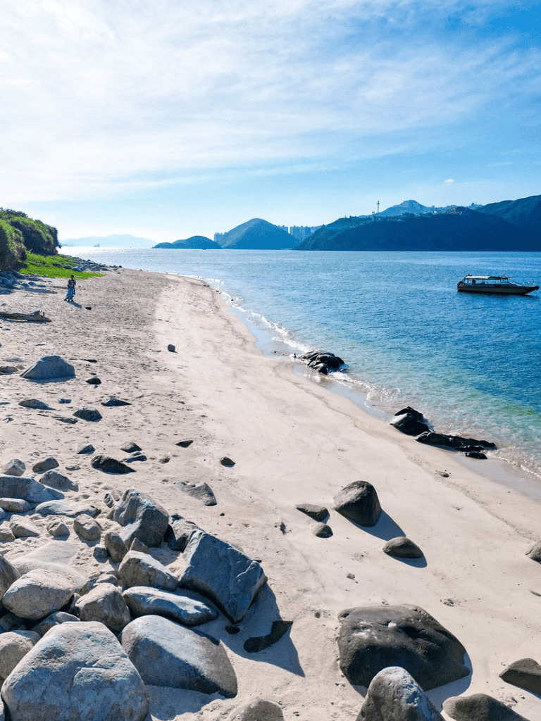Serene beach with clear blue water and scenic mountain views for travel and adventure.