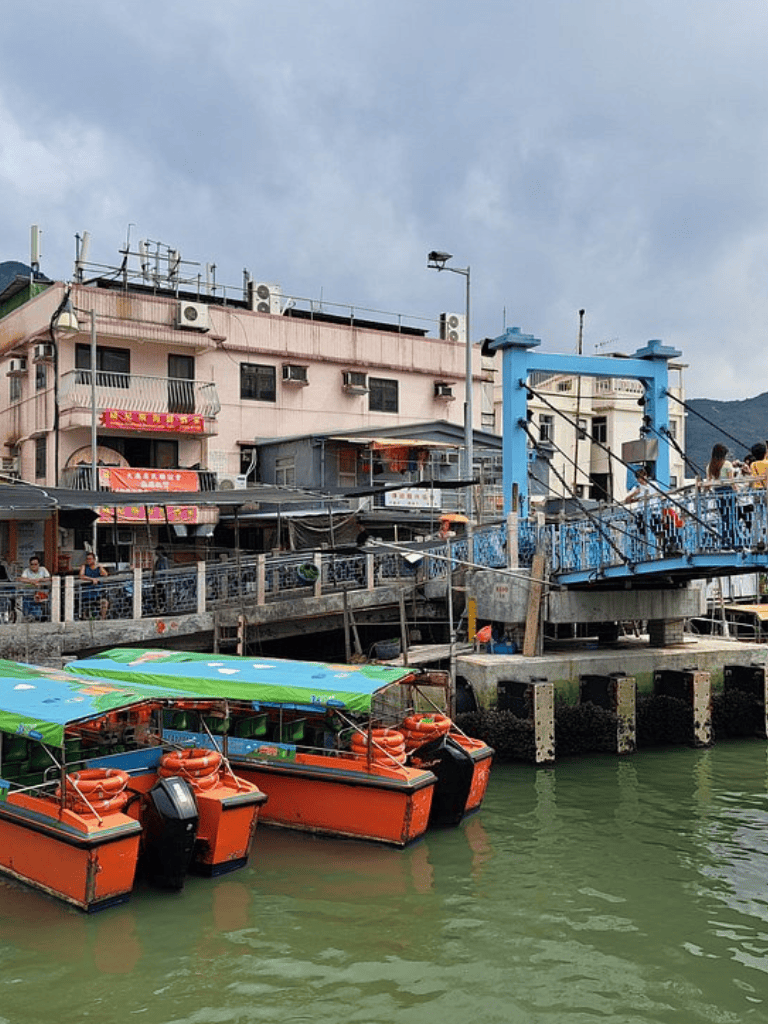 1. Small boats docked at a harbor near colorful buildings with a blue footbridge in the background.