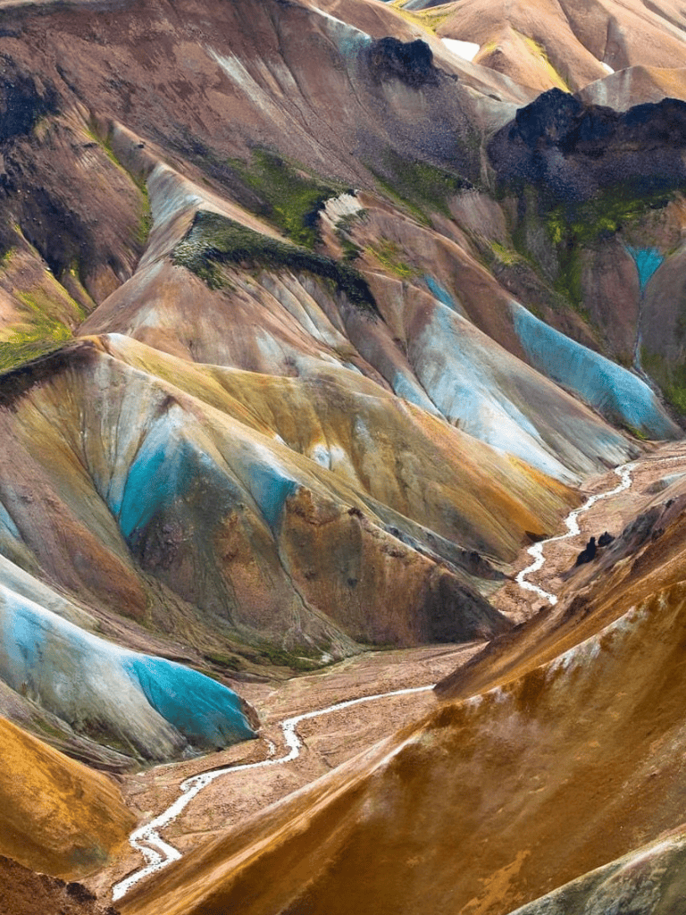 Colorful mountain landscape with vibrant hues and winding stream, Icelandic terrain, scenic hiking destination.