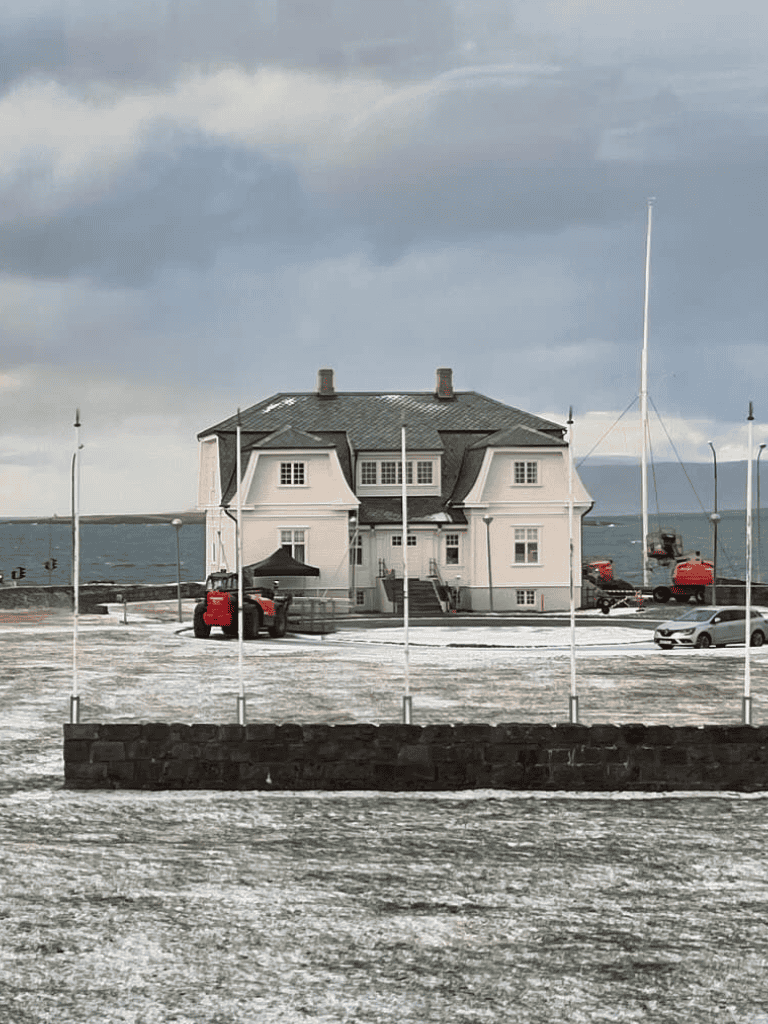 Flooded house by the sea with boats and stormy sky, scenic coastal weather.