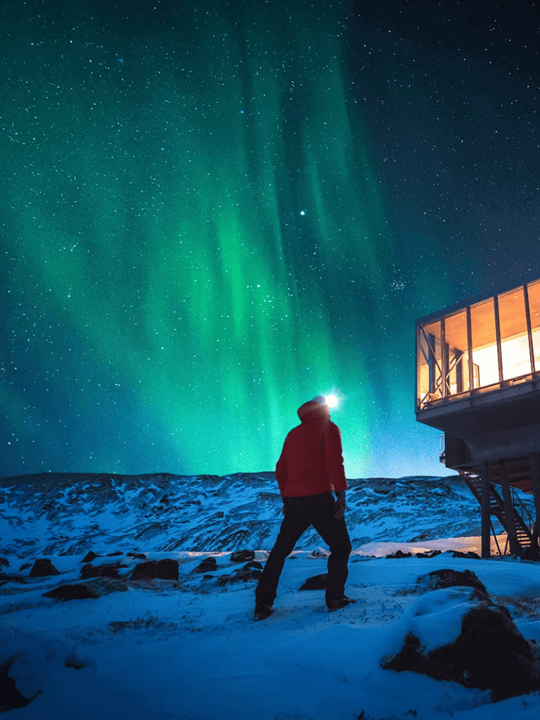 Northern Lights over snowy landscape with person viewing Aurora Borealis at QuestForDirections.