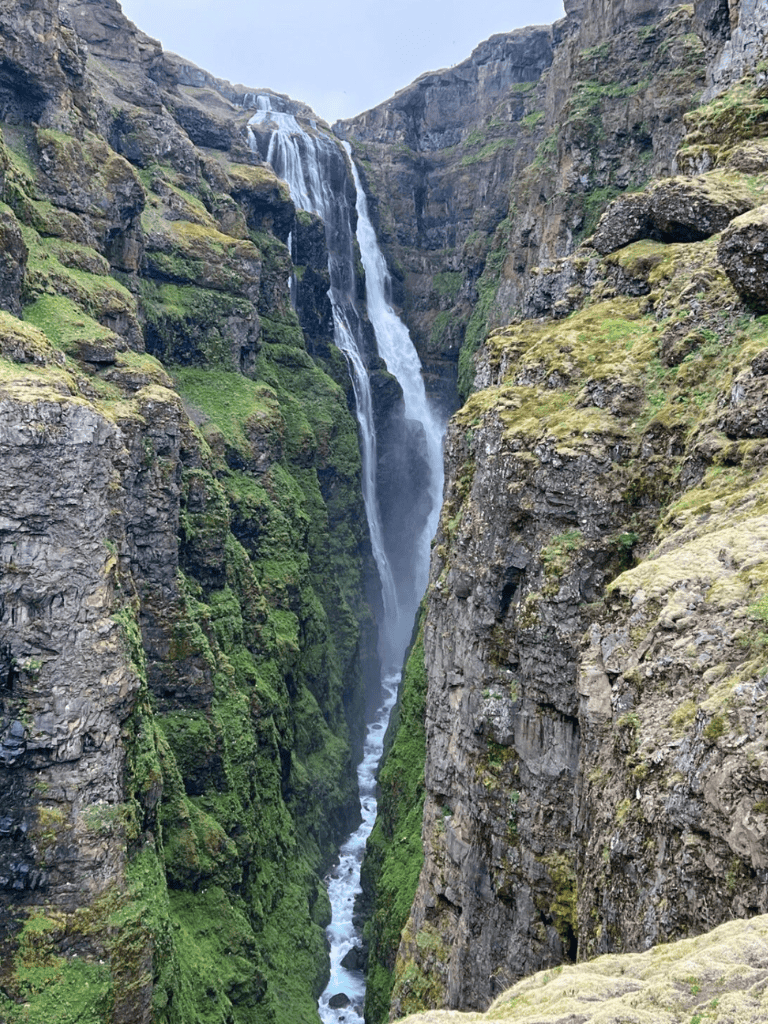Vökufoss Waterfall, Iceland, surrounded by moss-covered cliffs and rugged landscape.
