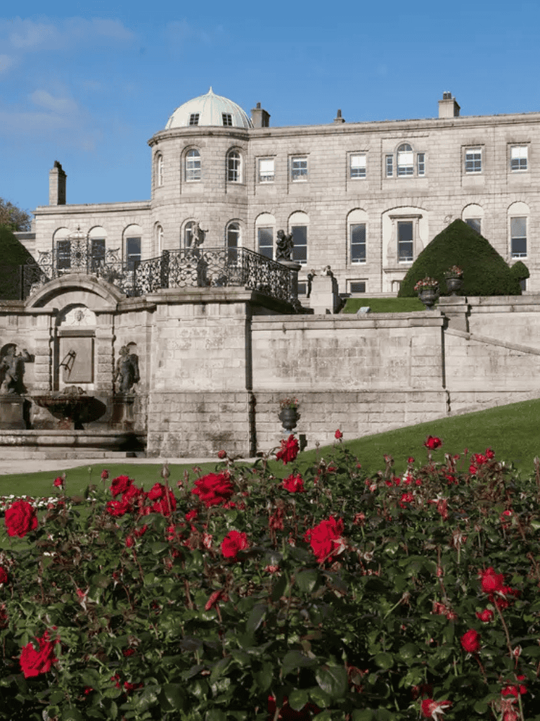 Elegant historic mansion with garden and red roses, featuring classic architecture and scenic views.