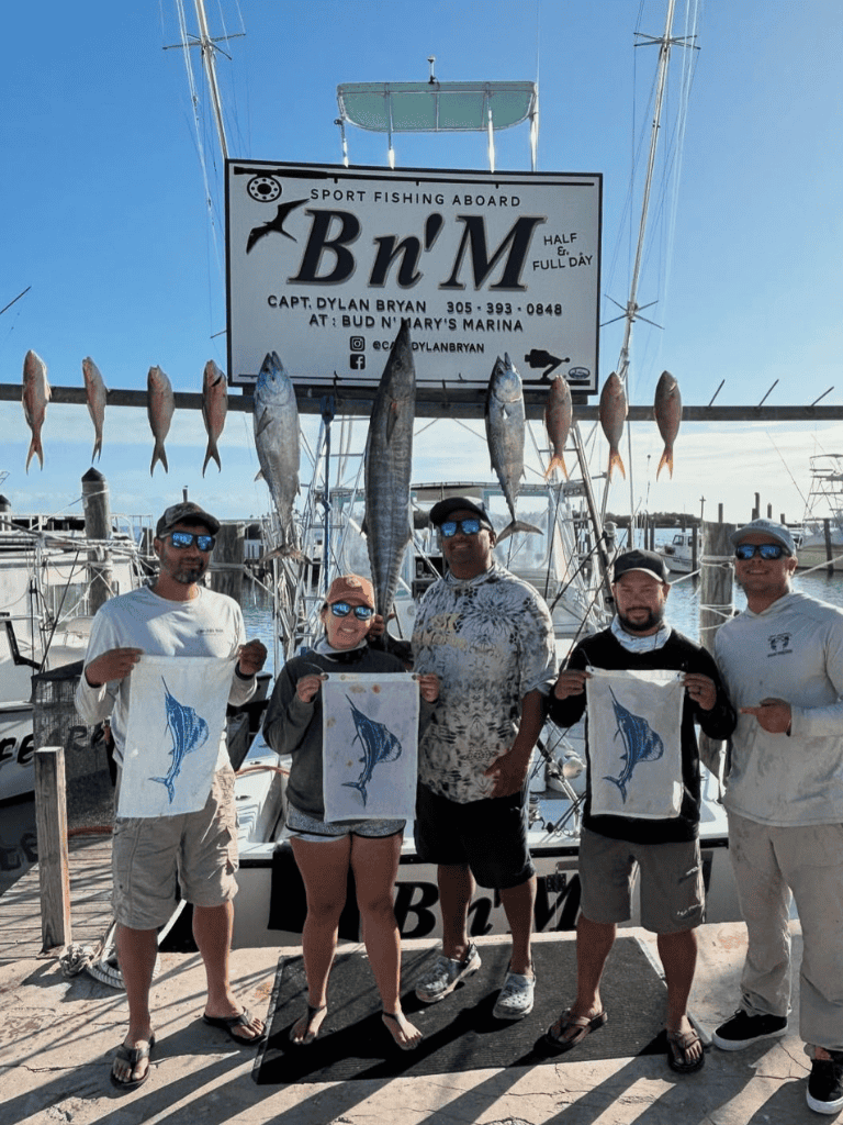 Biggest fishing catch at Bn'M Sport Fishing Aboard in Florida with group holding marlin flags.
