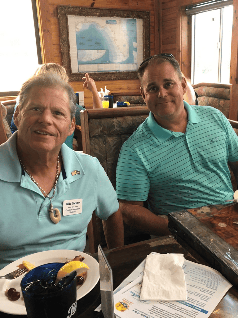 Smiling men at a restaurant table, enjoying a meal during a memorable gathering.