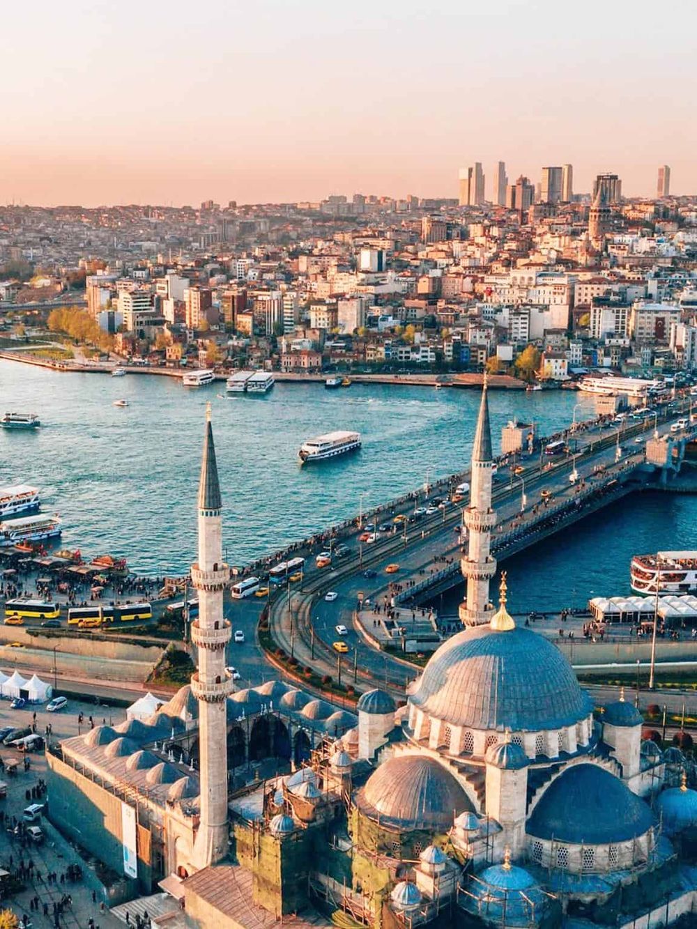 Aerial view of Istanbul with the Blue Mosque, Bosphorus Bridge, and city skyline at sunset.
