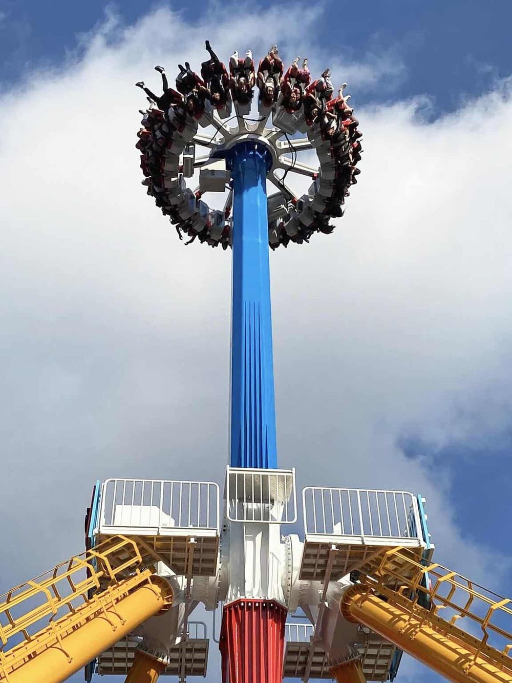 Thrilling amusement park ride with people swinging in a circular motion against a blue sky.
