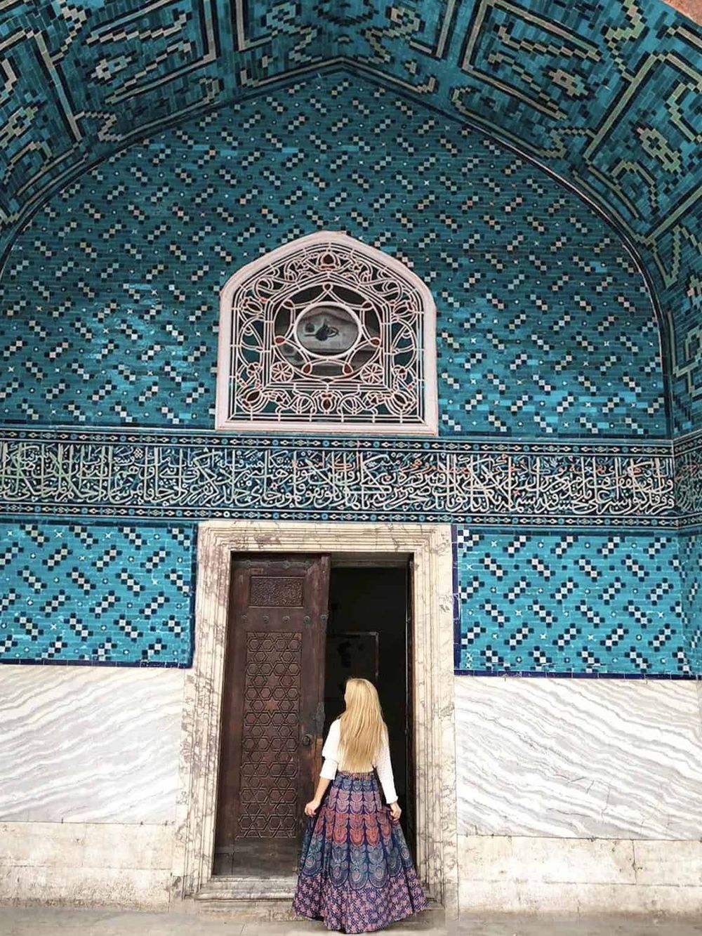 Intricate blue tile mosque with ornate Islamic calligraphy and architectural details, showcasing cultural heritage.