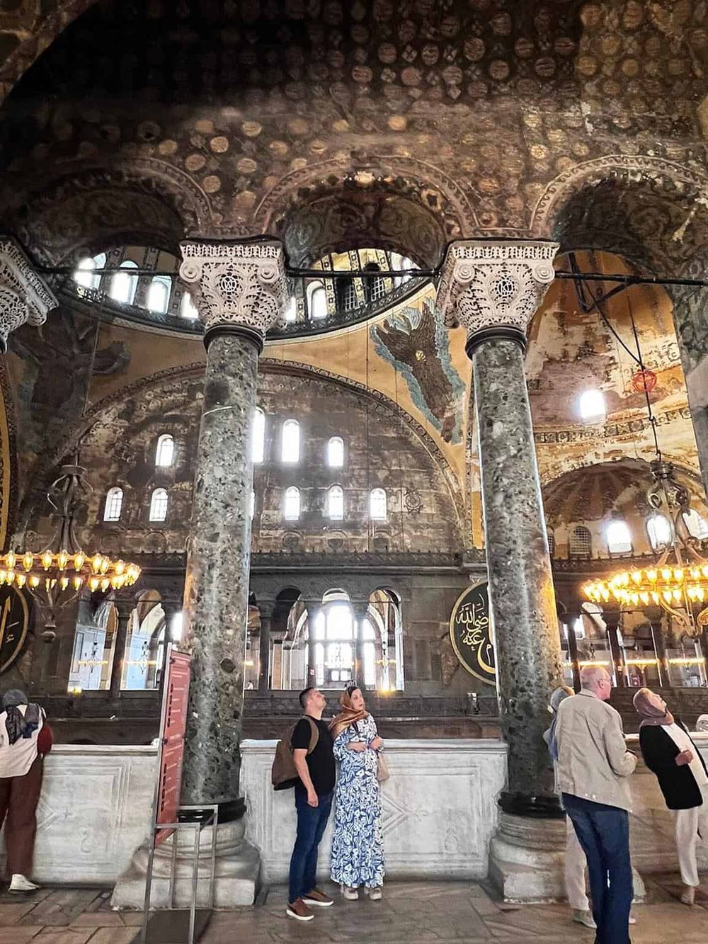 Ancient Mosque interior with ornate pillars, domed ceiling, and visitors exploring the historic site.