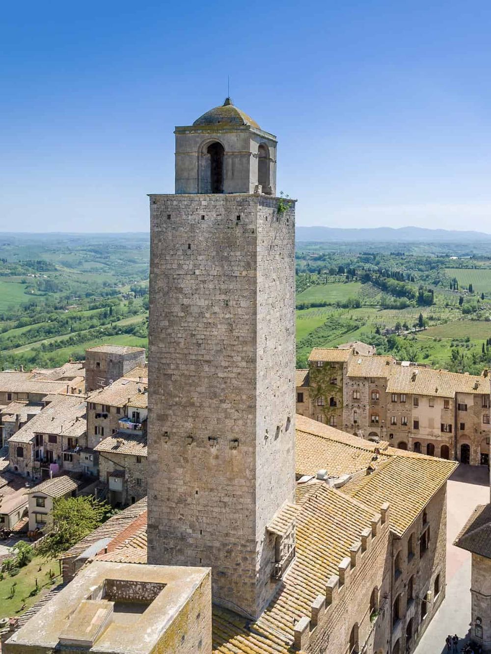 Ancient stone tower in Italy with scenic countryside view, historic architecture, and clear blue sky.