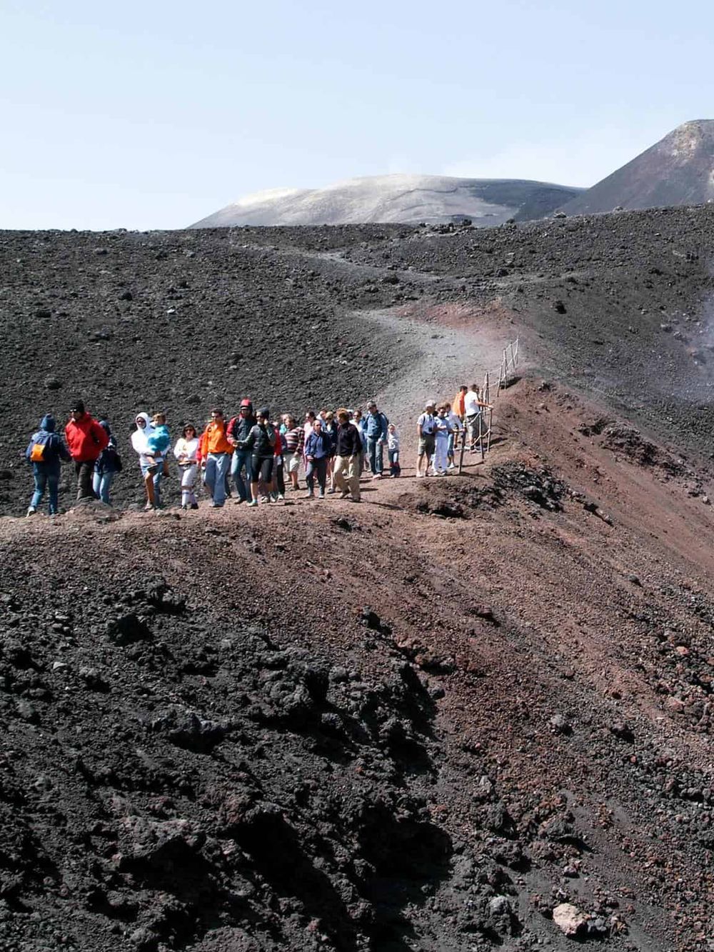 People hiking on volcanic terrain with a ladder in a scenic volcanic landscape.