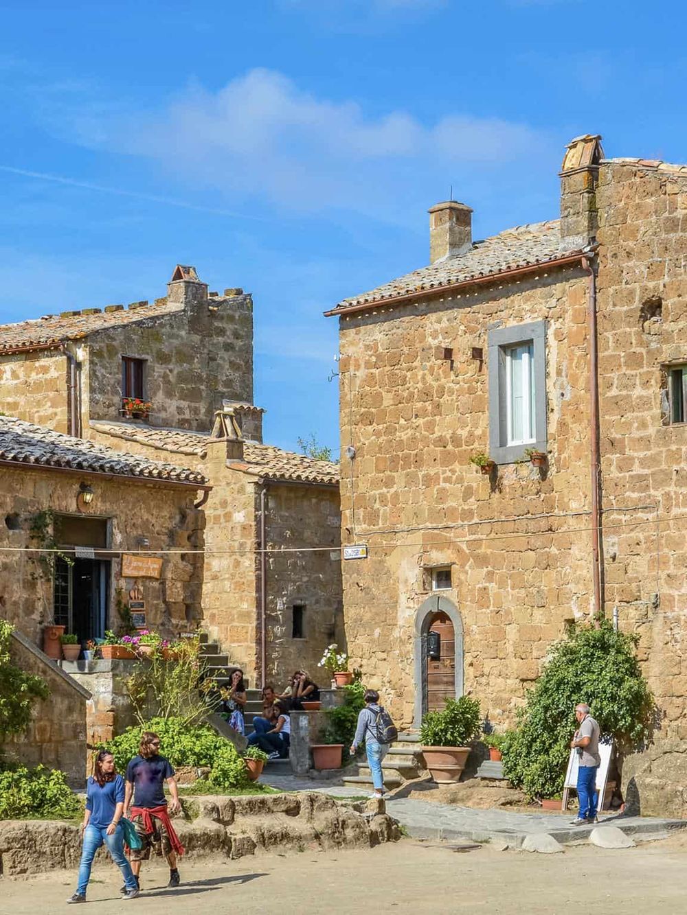 Charming old stone buildings in a historic European village with tourists exploring the area.