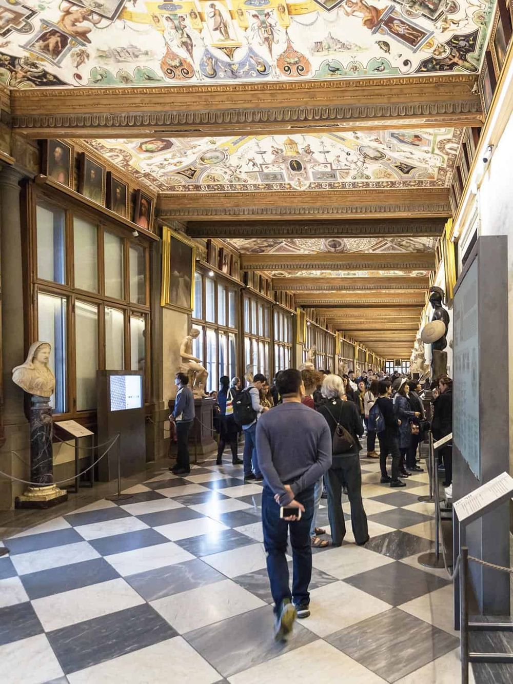 Imposing museum interior with classical artwork and visitors exploring history exhibits.