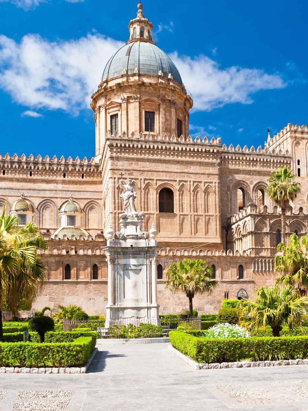 Spectacular view of a historic cathedral with domed architecture, lush greenery, and bright blue sky, perfect for travel exploration.