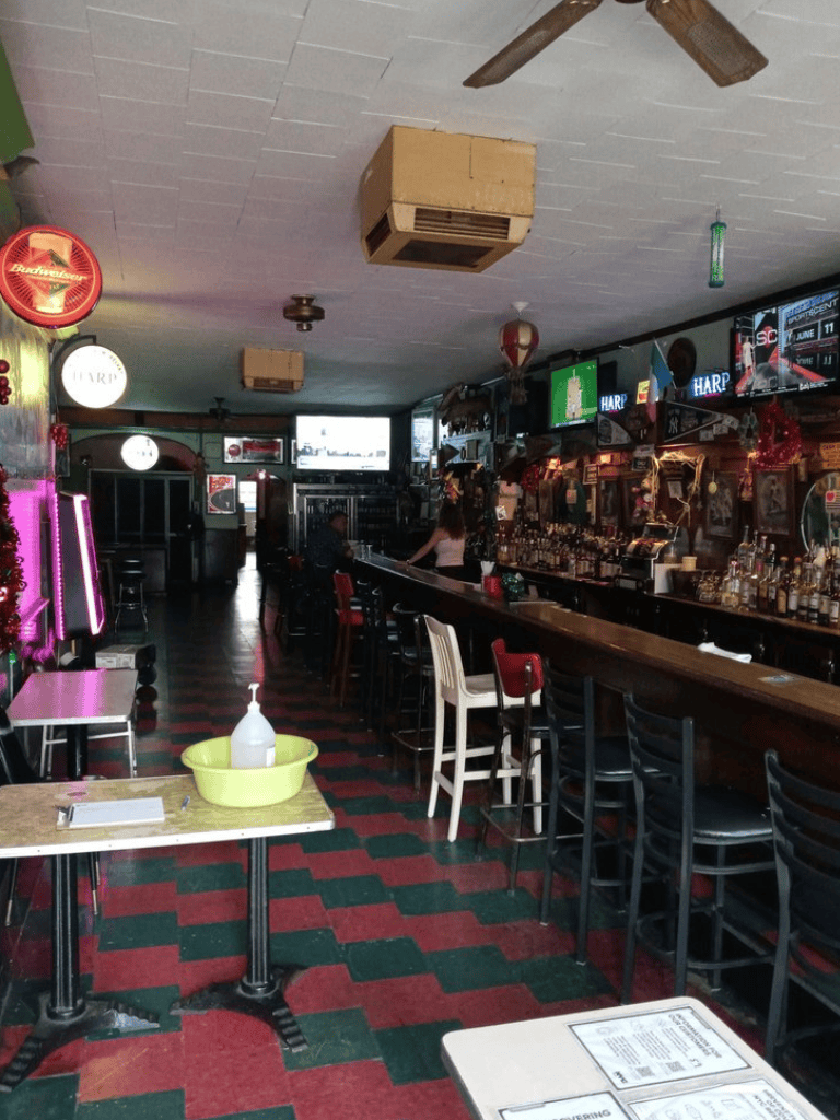 Cozy bar interior with colorful decor, multiple TV screens, and seating area for social gatherings.