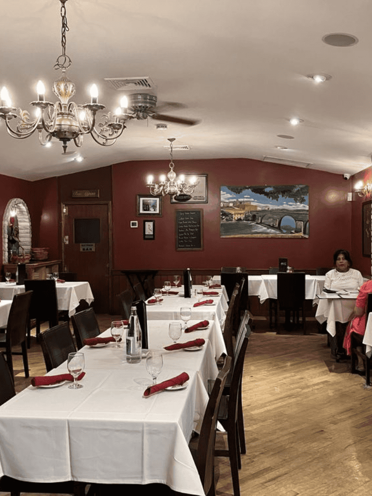 Elegant restaurant interior with white tablecloths, red napkins, and dim lighting for dining at QuestForDirections.