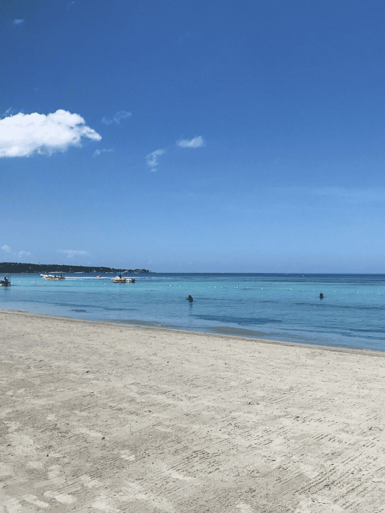 Serene beach with clear blue water and boats, perfect for relaxing and exploring coastal destinations.