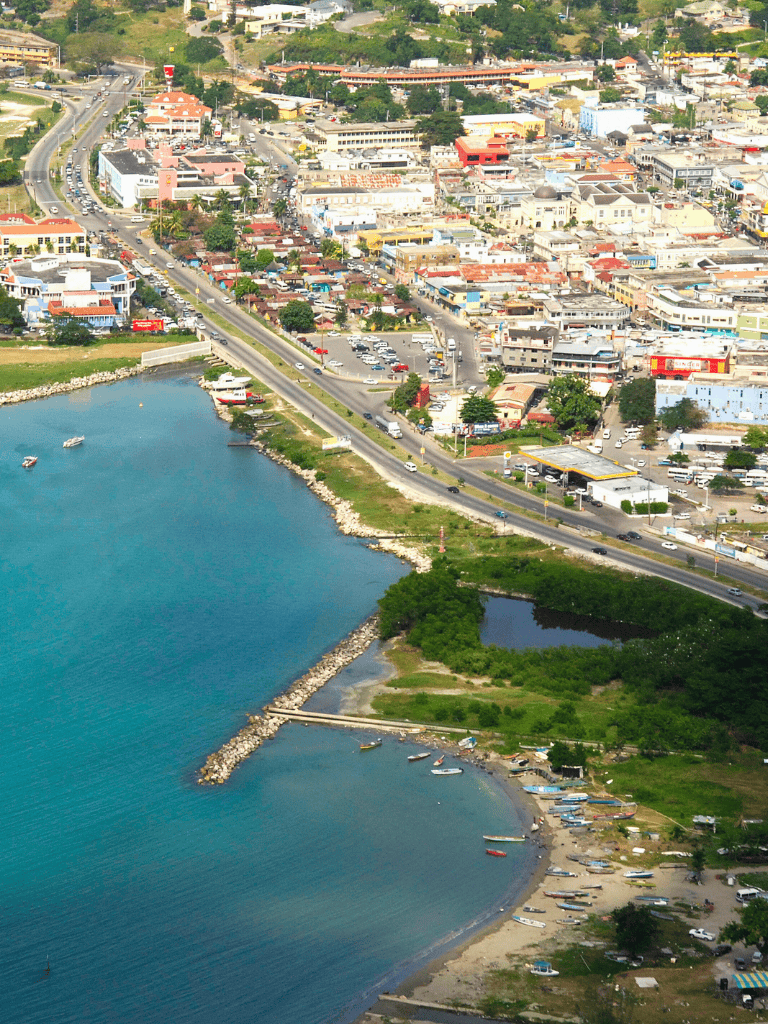 Aerial view of a coastal city with vibrant buildings, water pier, and busy roads, showcasing urban development and waterfront scenery.
