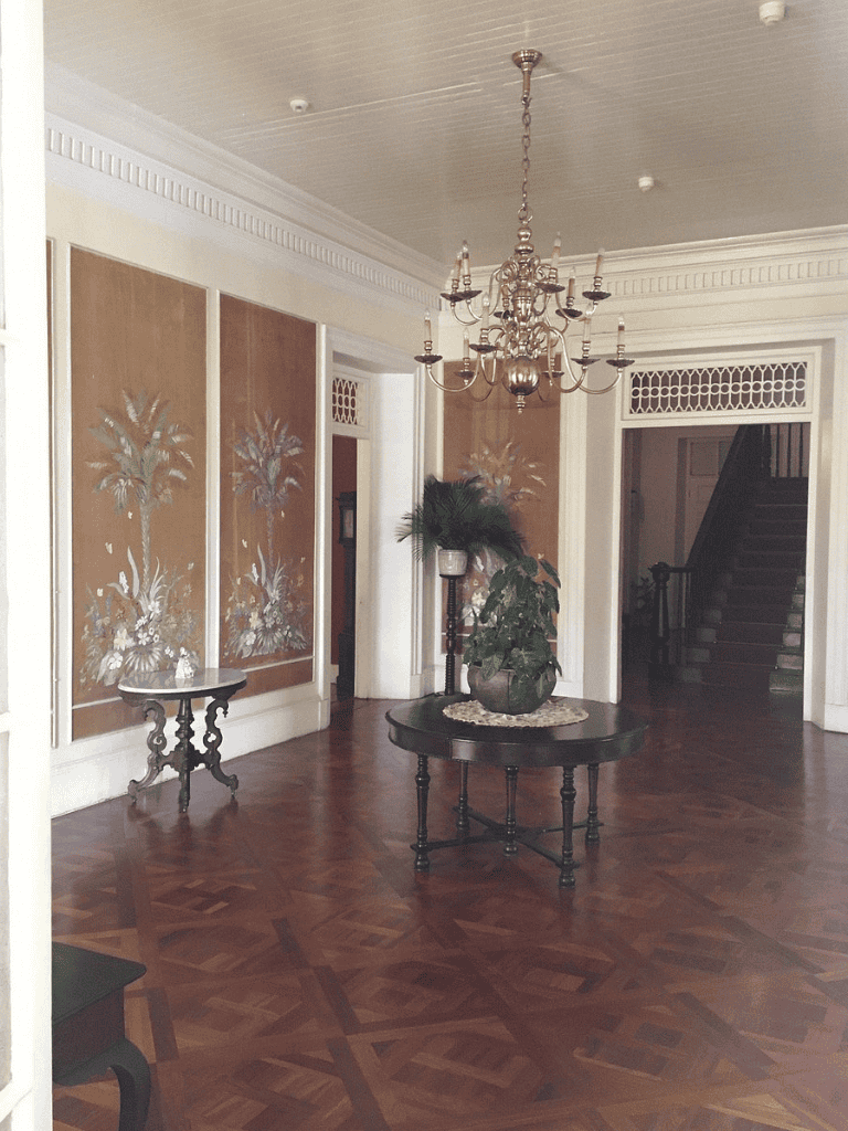 Elegant foyer with chandelier, antique tables, and hardwood flooring, showcasing classic interior design.