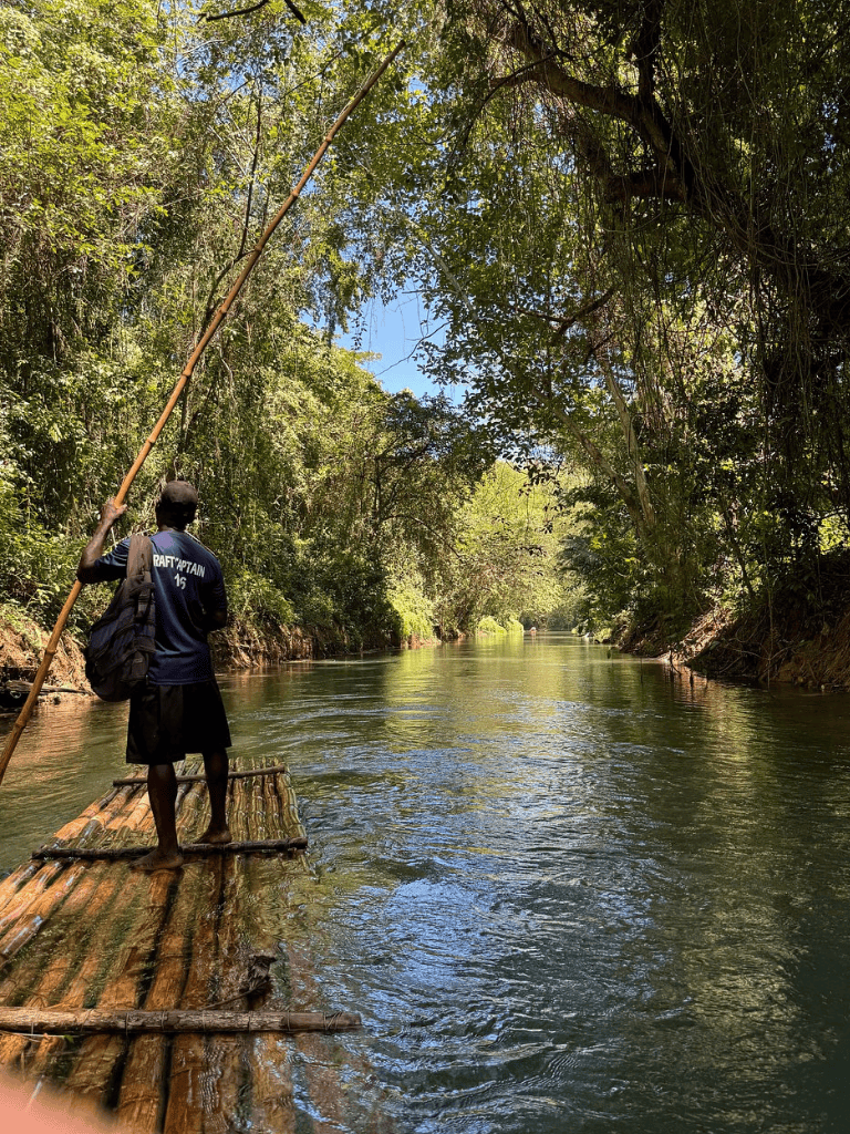 Riverside jungle adventure featuring a raft captain navigating lush greenery and calm waters for eco-tourism.