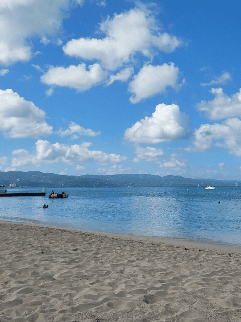 Calm beach with blue skies and white clouds, scenic waterfront view, ideal for relaxing and exploring coastal destinations.