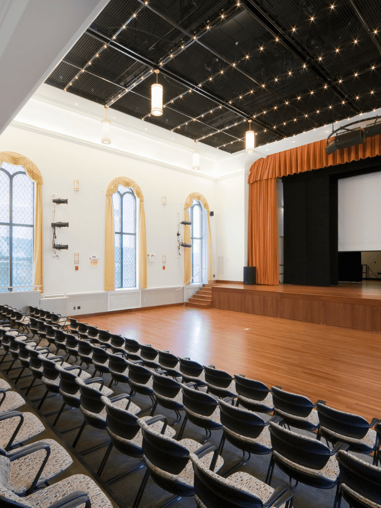 Elegant event hall with stage, seating, and lighting for conferences, weddings, and corporate events.