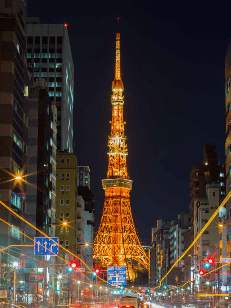 Brightly illuminated Tokyo Tower at night with surrounding cityscape and traffic lights.
