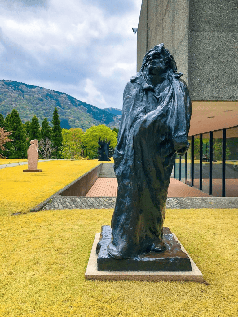 Bronze statue of a man with mountains and greenery in background at QuestForDirections.