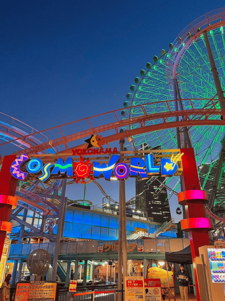 Brightly lit Yokohama Cosmo World Ferris wheel at night, popular attraction in Japan.