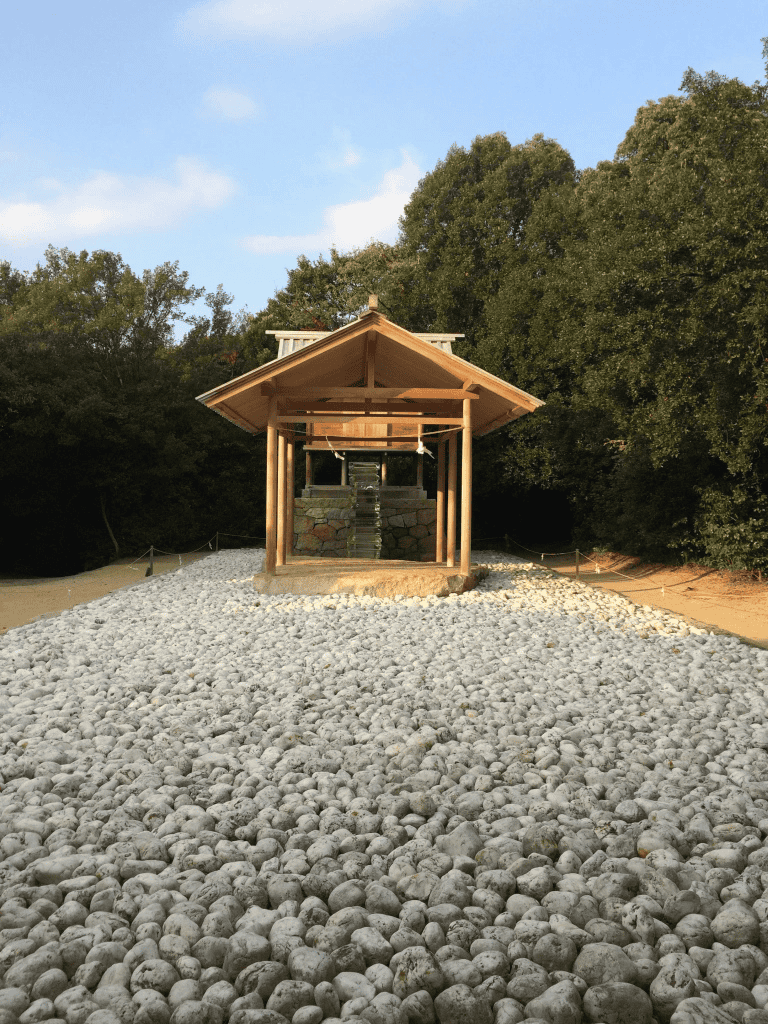Raised wooden shelter under construction on rocky pathway surrounded by trees.