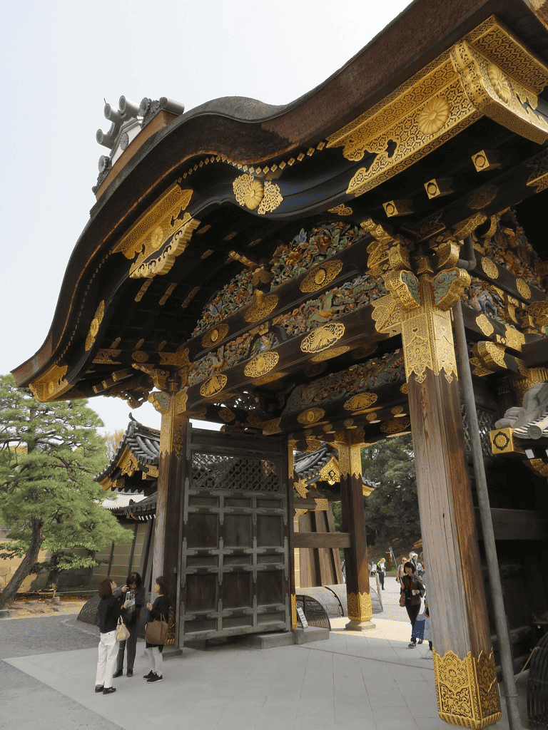 Intricate wooden temple gate with gold embellishments at a historic Japanese site.